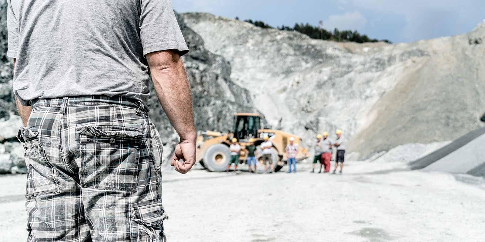 Bagger und Baurabeiter in einem Steinbruch